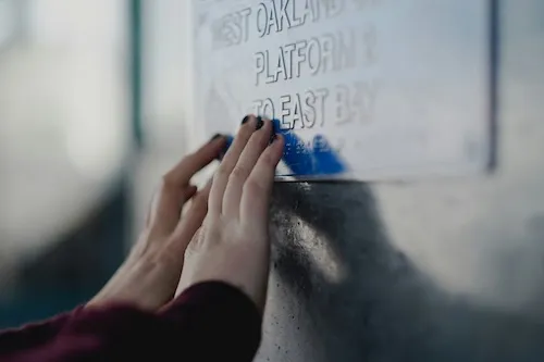 Hände ertasten Braille-Schrift auf einem Hinweisschild